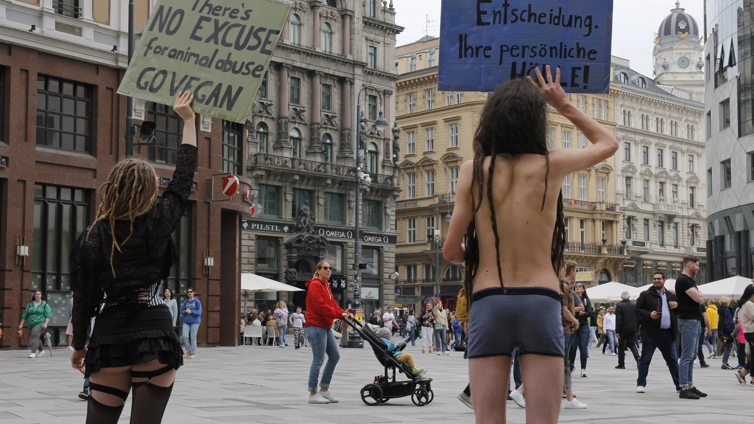 Aktivist:innen stehen bei einem Lingerie Protest mit veganen Schildern im öffentlichen Raum.