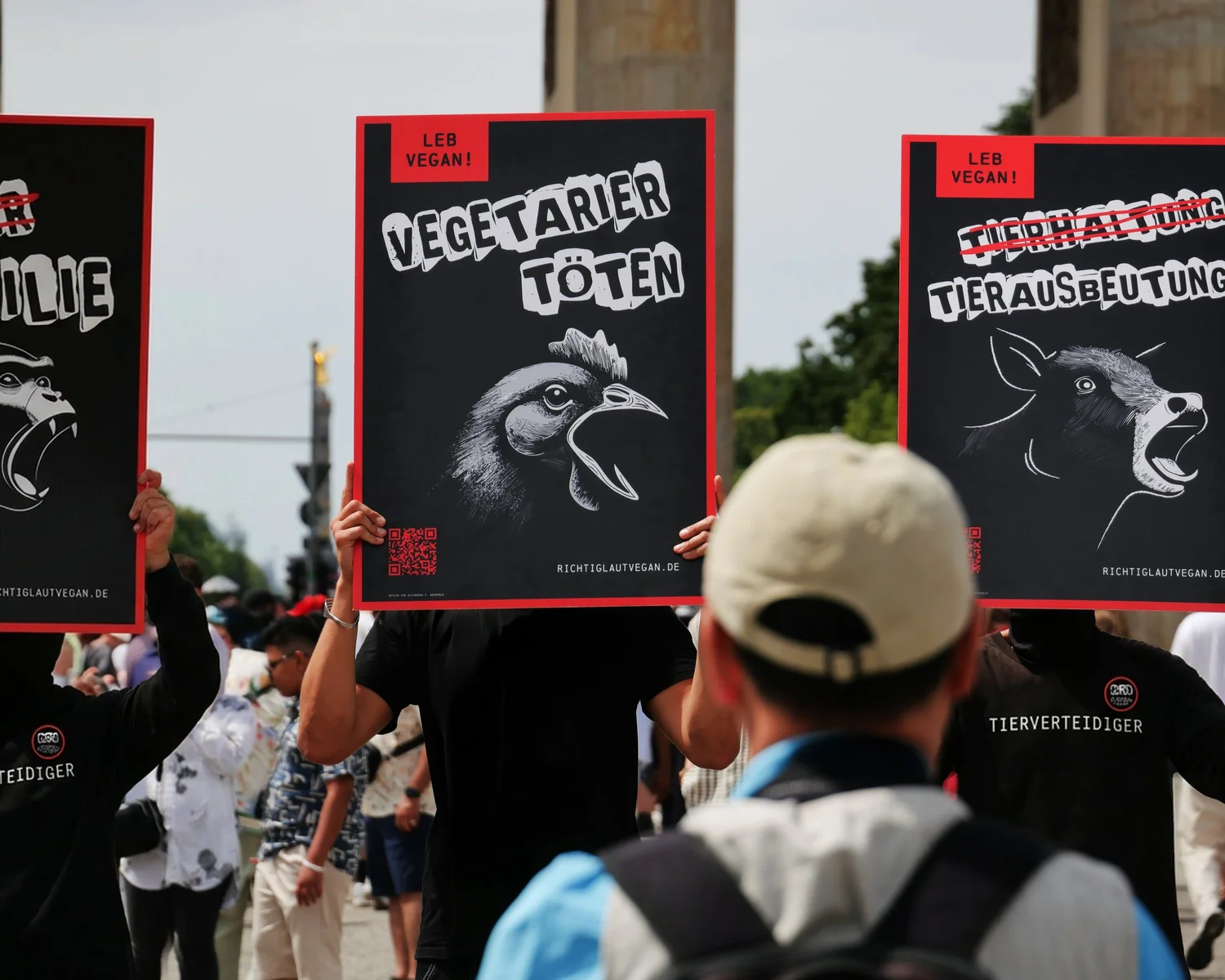 Schwarz gekleidete NEON-Aktivist:innen stehen mit Schildern bei einem Protest im öffentlichen Raum.