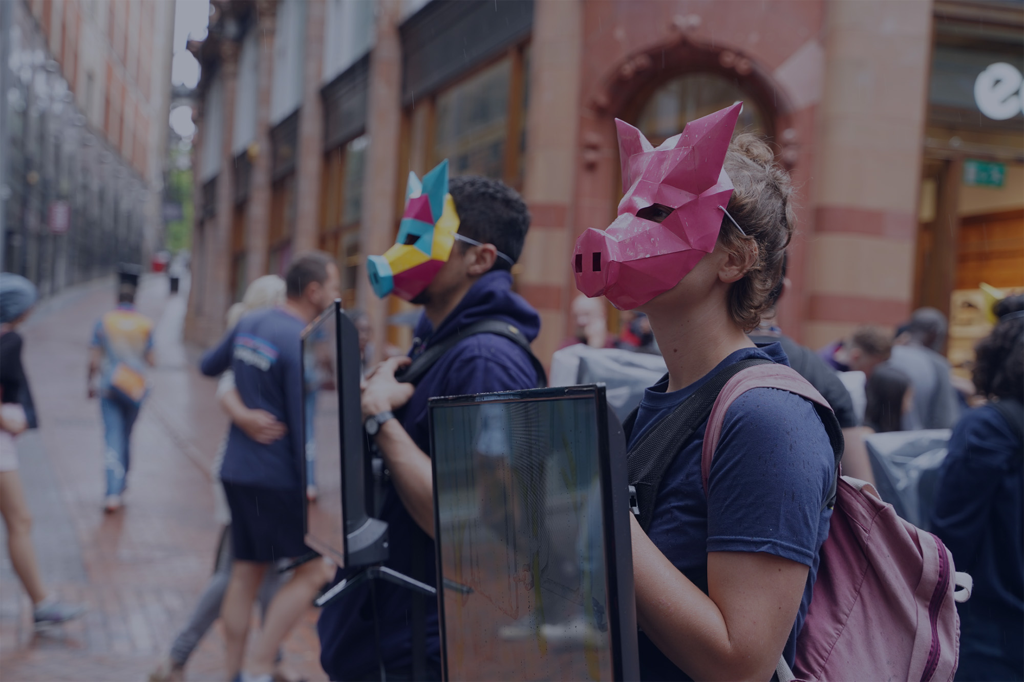 We The Free Aktivist:innen stehen bei einem WTF Diamond mit Bildschirmen und Masken im öffentlichen Raum.